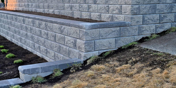 A close-up capture of a gray colored retaining wall built as a two tier wall in block shape stone material stacked following a clear professional design.